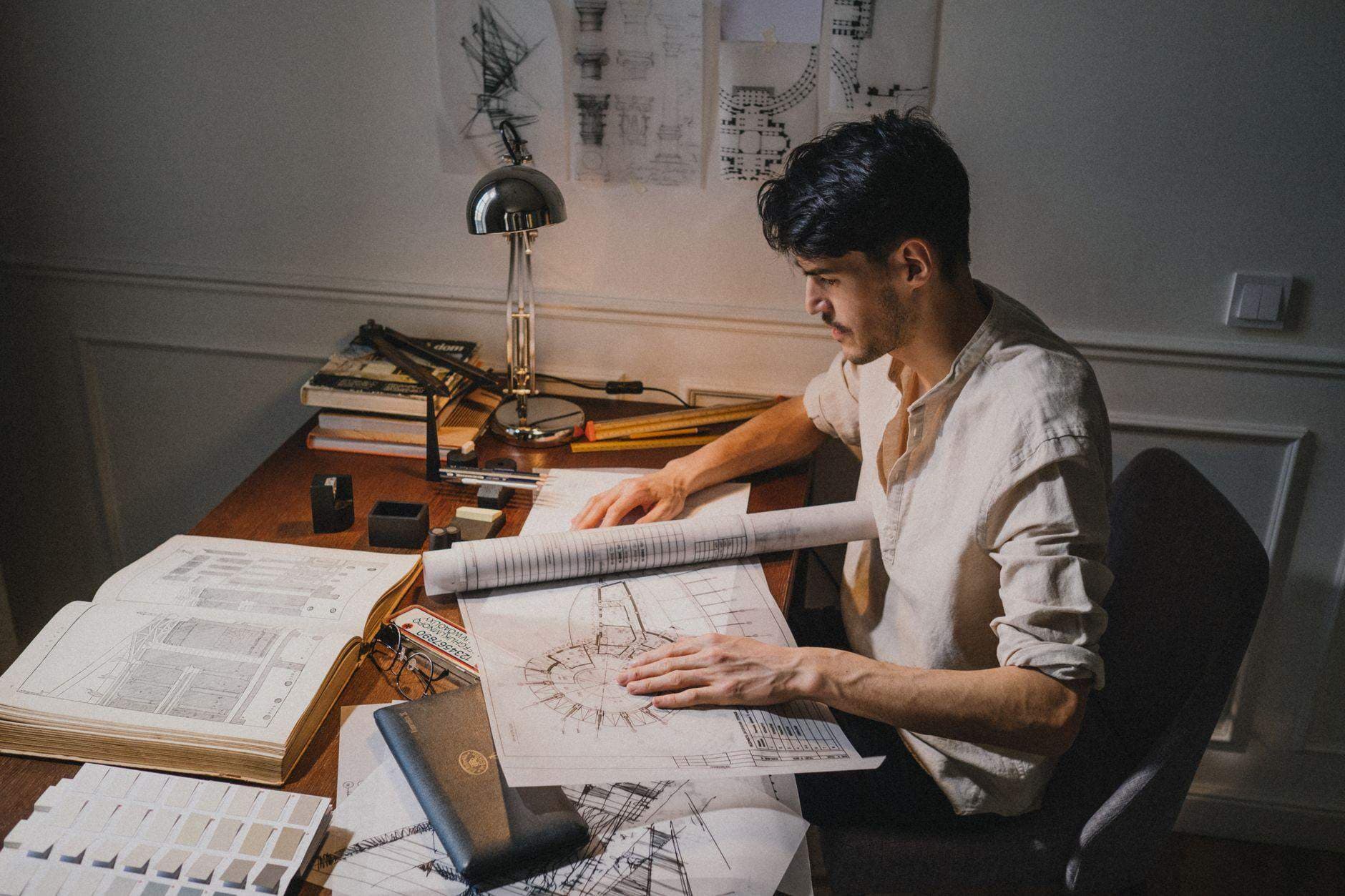An architect reviewing blueprints spread across a drafting table